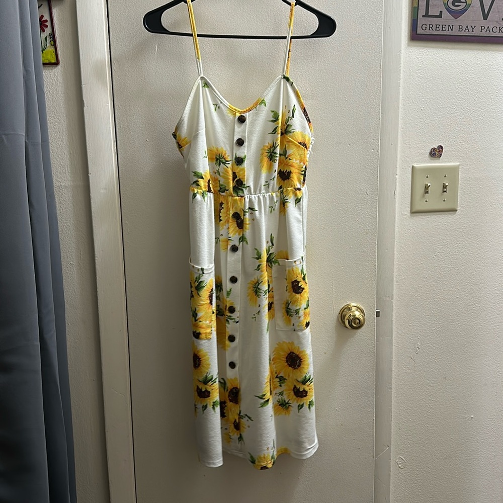 Spaghetti strap sunflower dress with two pockets.